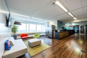 Moderne, licht ingerichte kantoorlounge aan de Johan Huizingalaan met zithoek, keuken en bar.